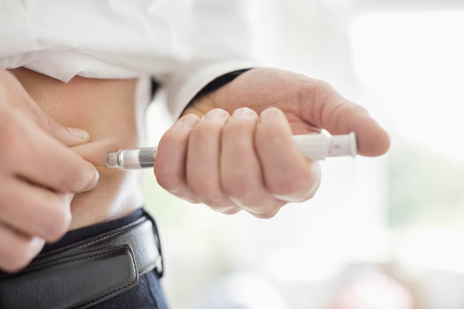 man injecting himself in the abdomen