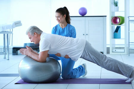 female nurse helping male patient with physical therapy