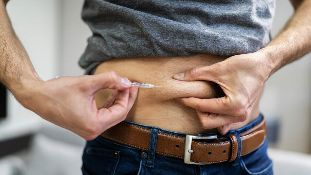 man giving himself an injection in the abdomen