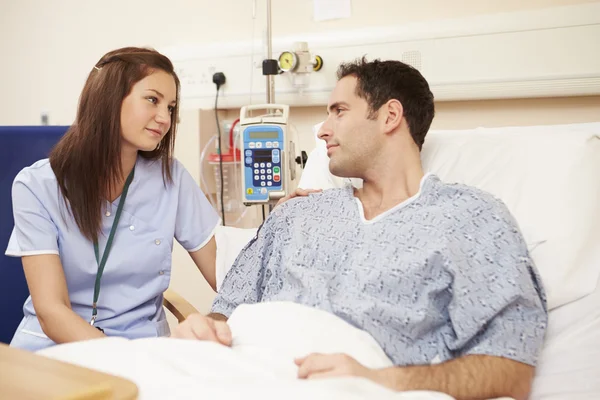 female nurse talking with male patient that is in a hospital bed