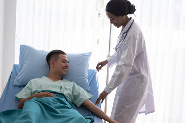 female doctor helping male patient in hospital bed