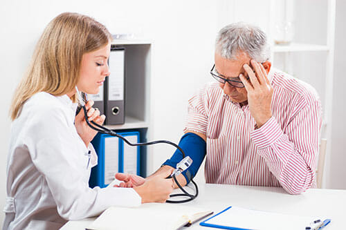 female doctor taking a male patients' blood pressure