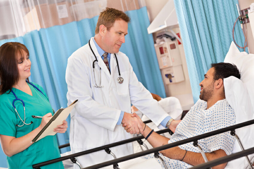 doctor and nurse talking to patient in hospital bed